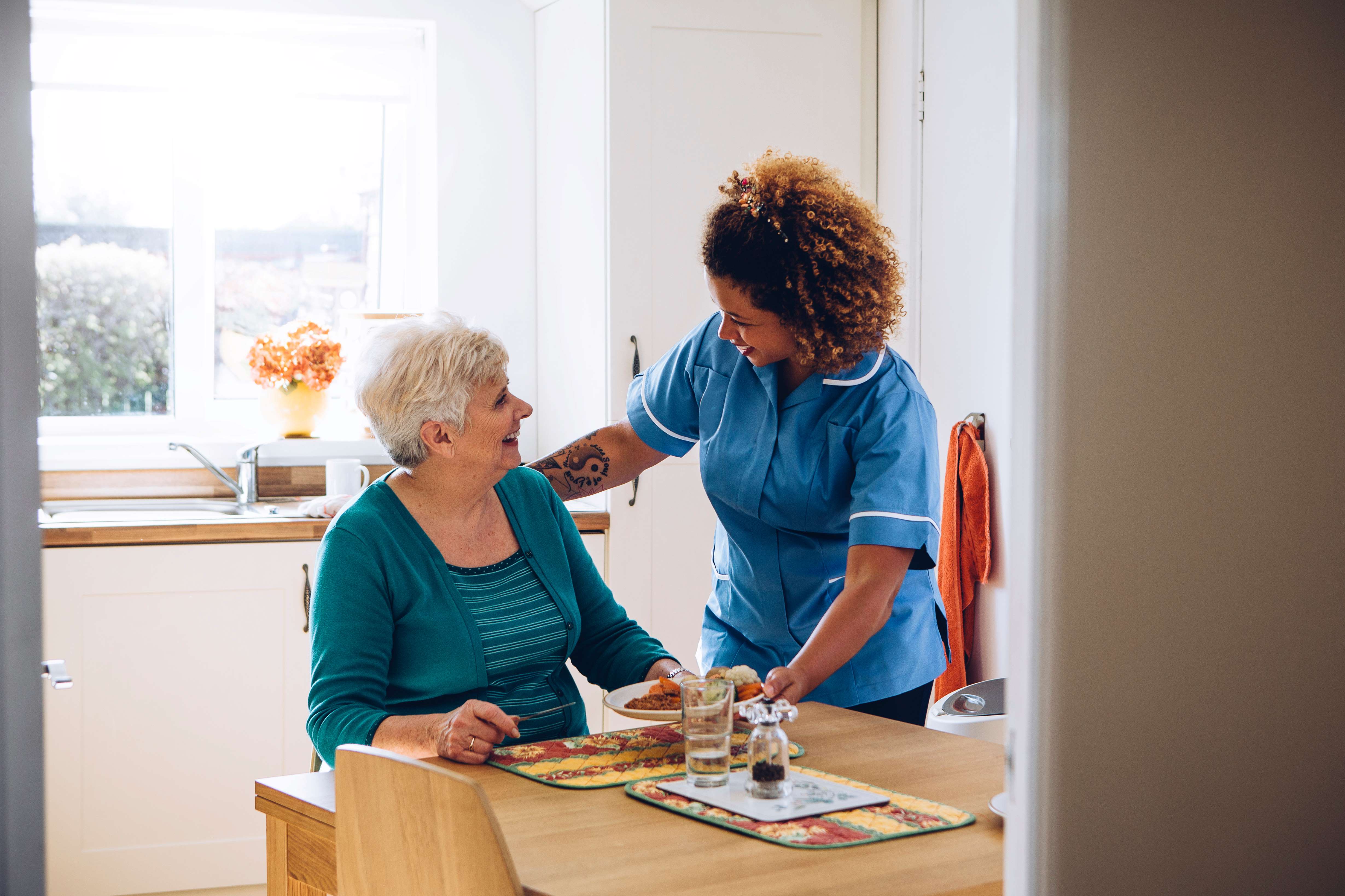 Carer with lady at her kitchen table