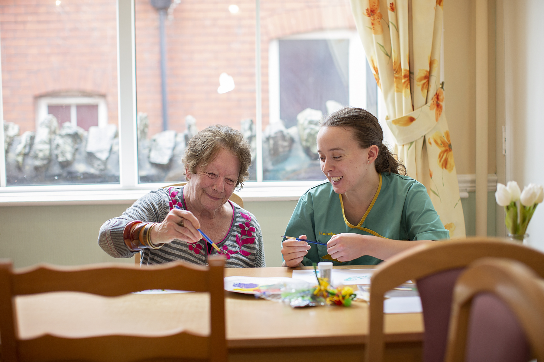 Carer and resident painting at Gwynfa Care Home