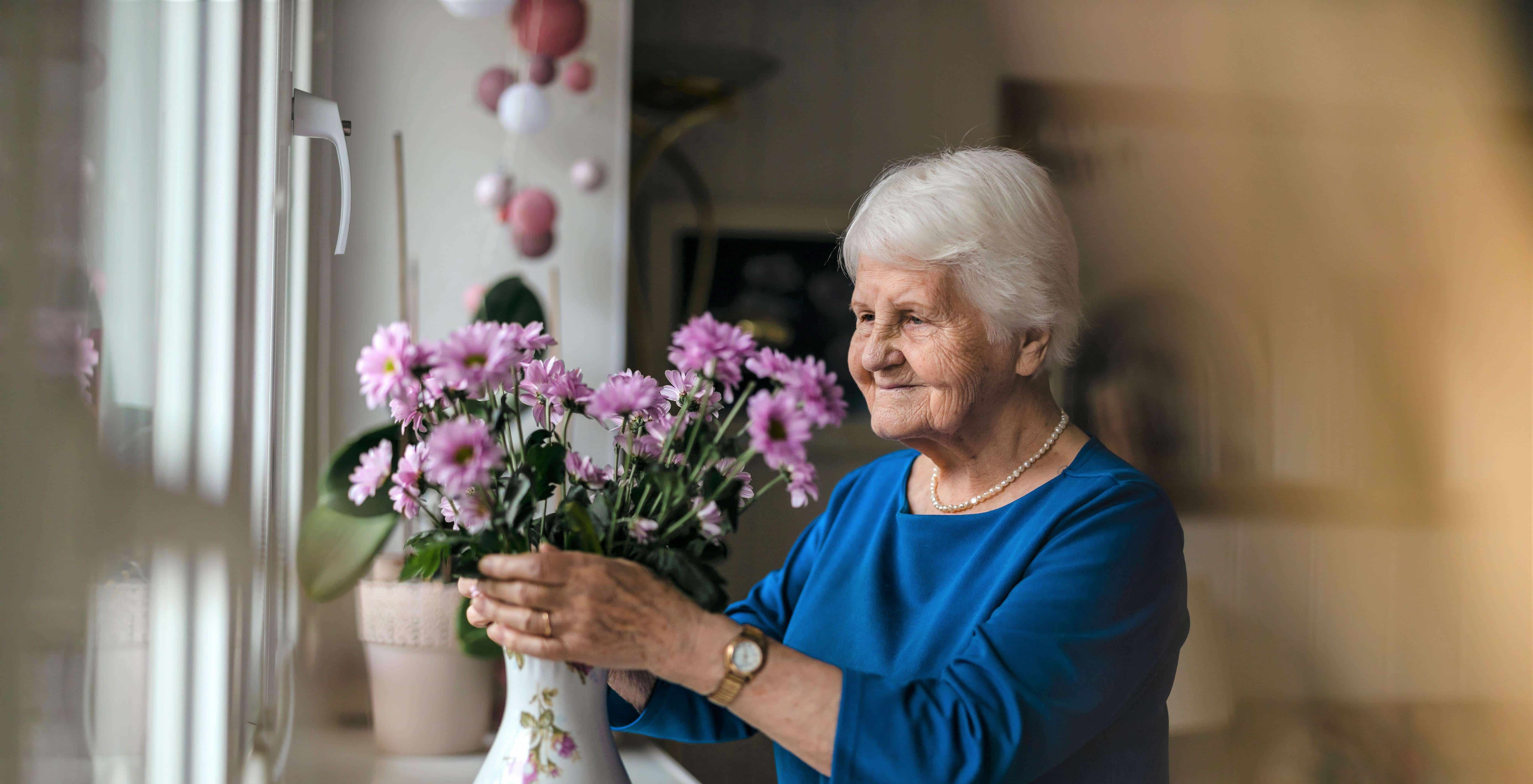 Lady adjusting flowers in a vase on the windowsill