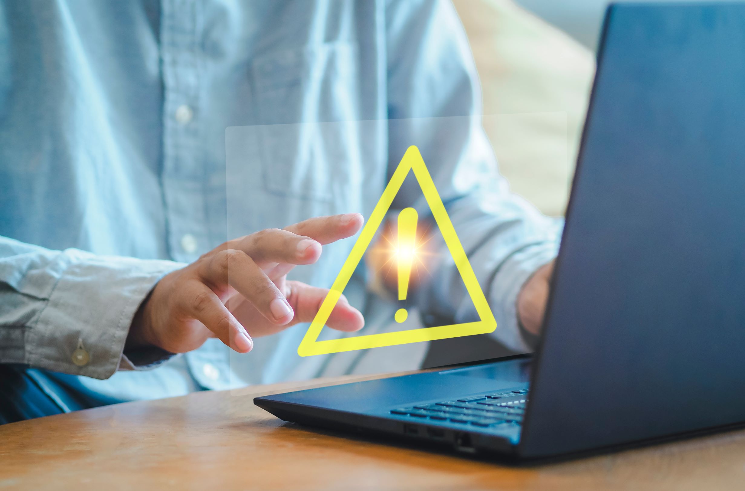 Man using a laptop with a warning sign