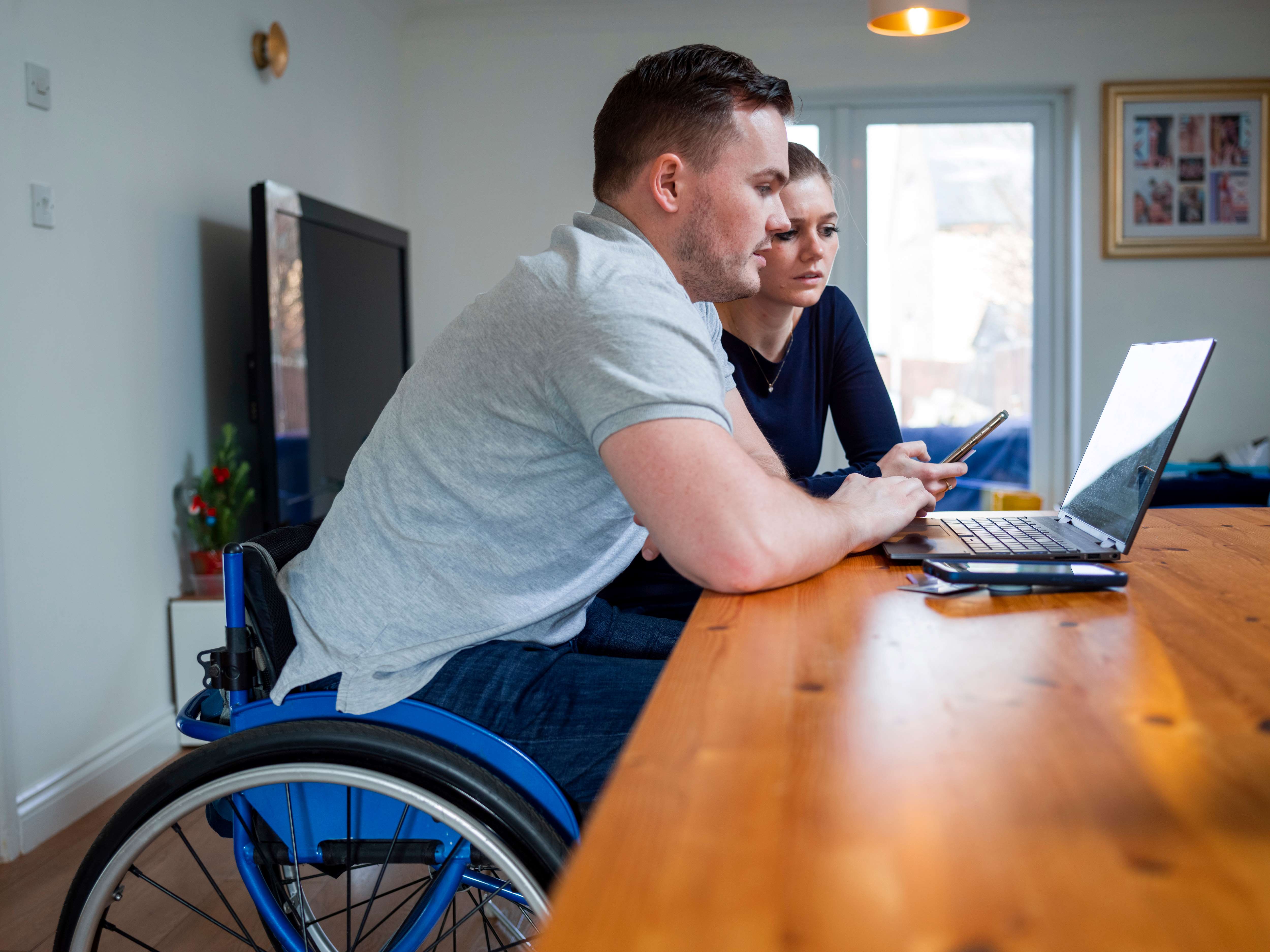 Man in wheelchair using laptop at the table