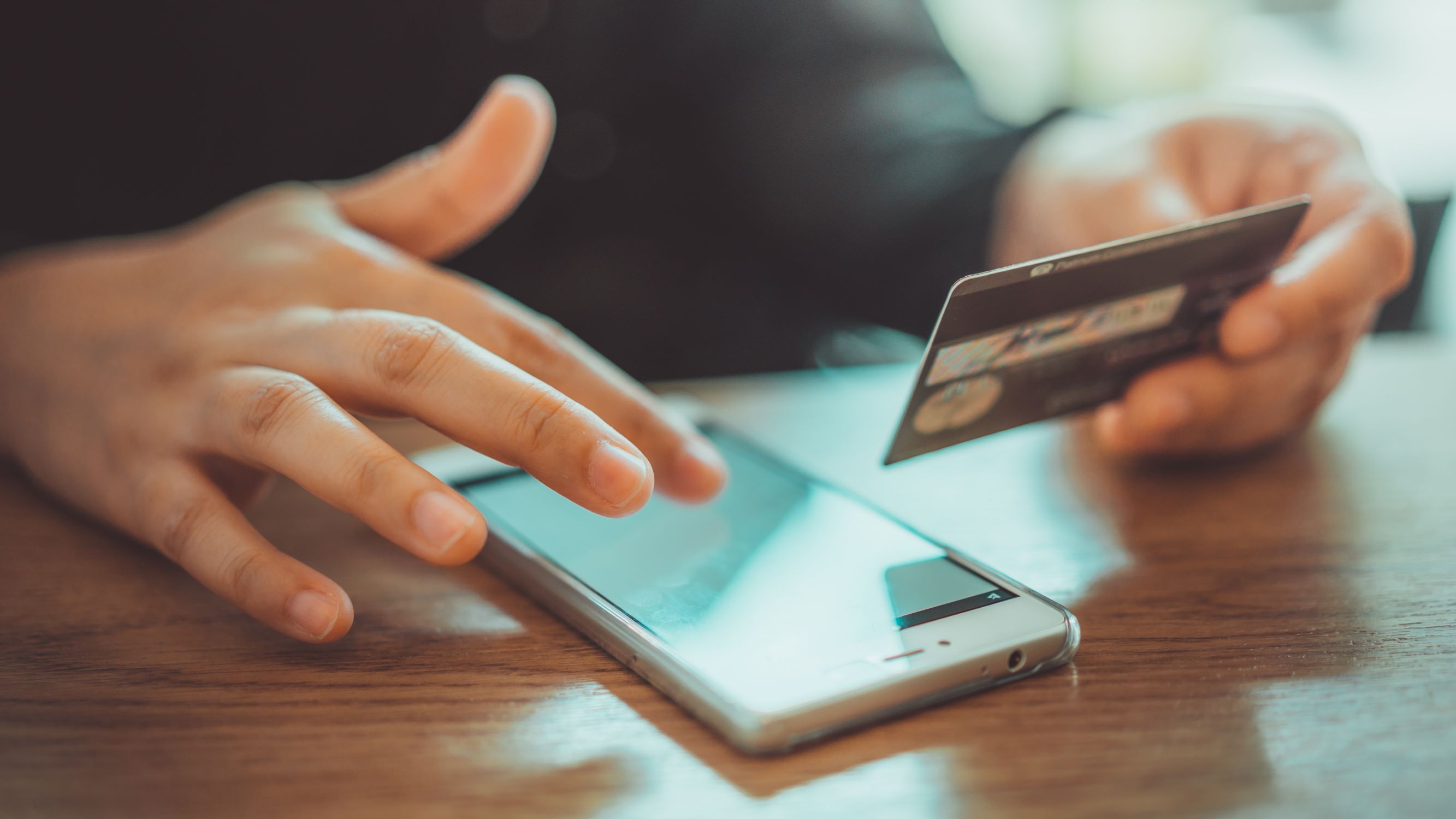 Man using phone for online shopping and holding his card to copy the details