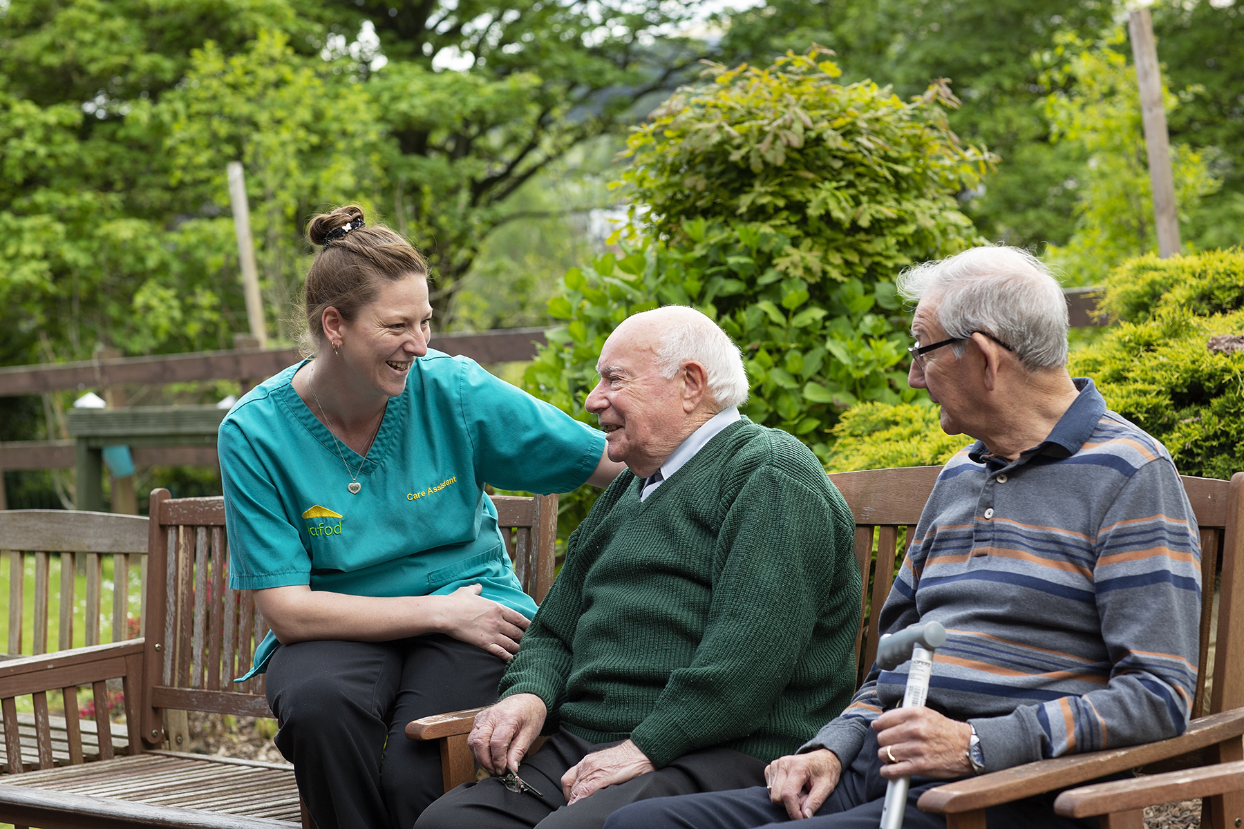 Residents and carer sitting outside in the garden at Plas y Garn Care Home