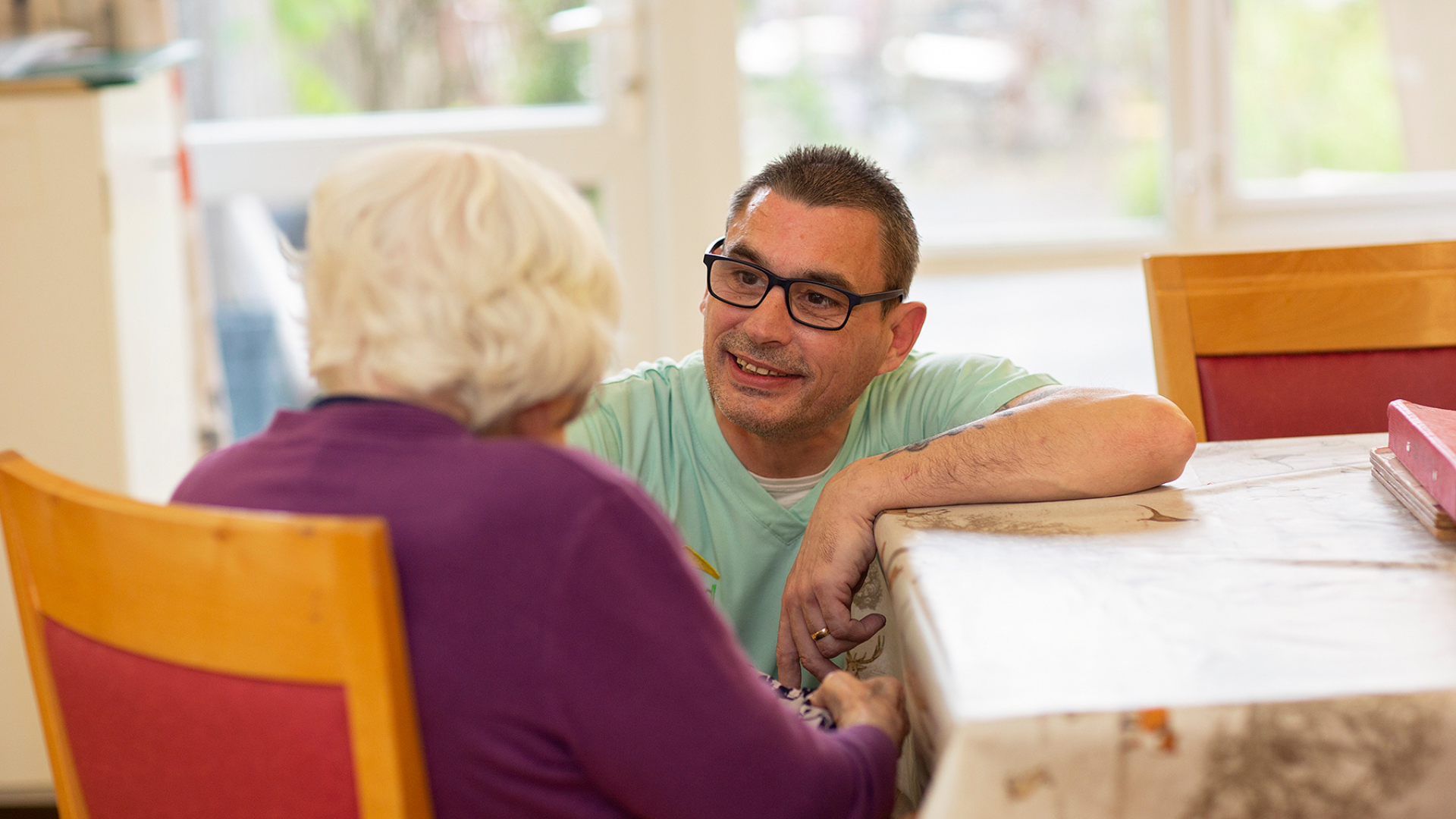 care worker and elderly resident at a table