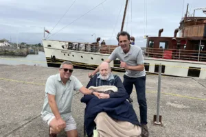 Three people on a dock beside the vintage ship Waverley