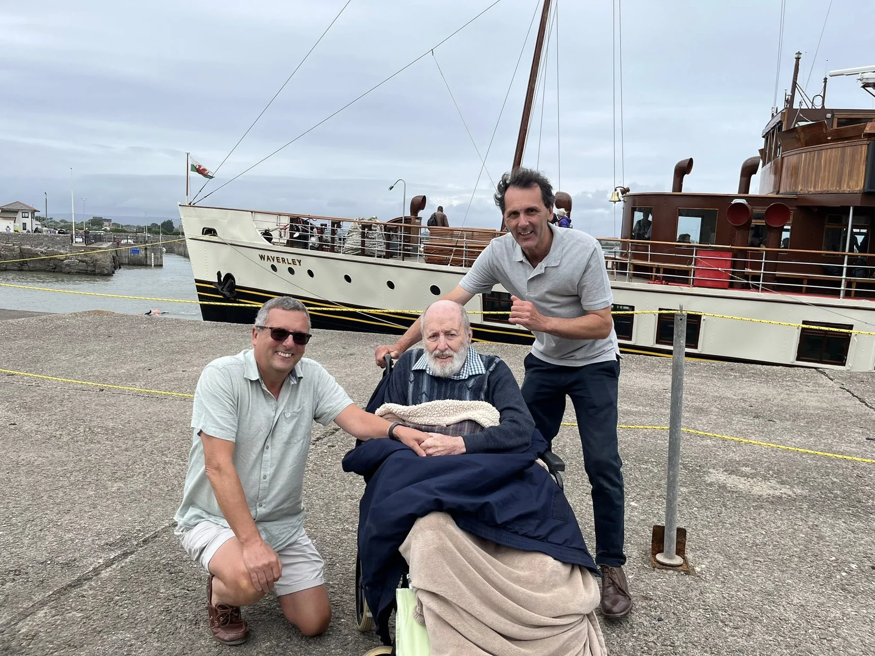 Three people on a dock beside the vintage ship Waverley
