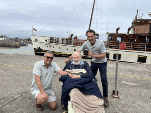Three people on a dock beside the vintage ship Waverley