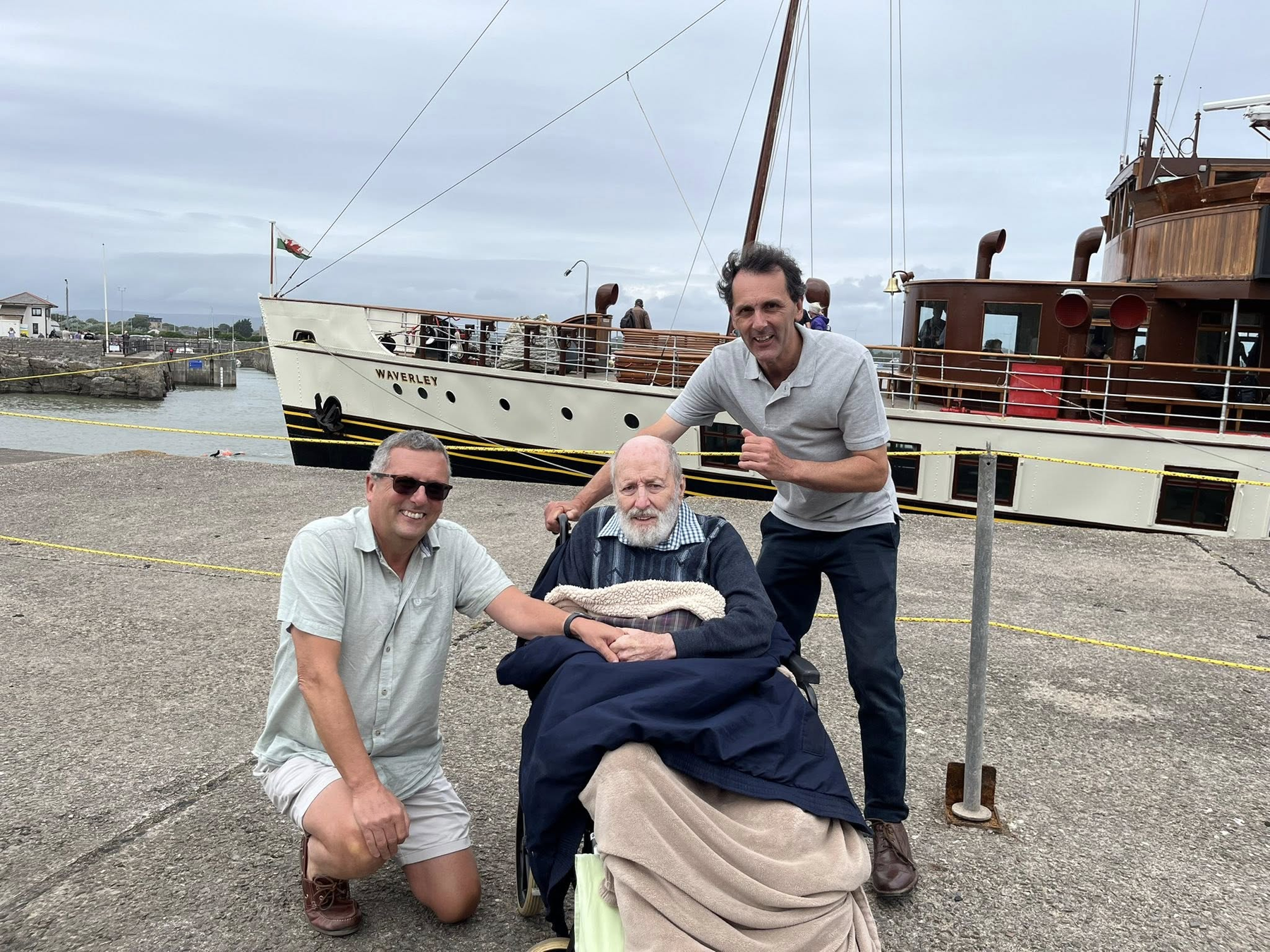 Three people on a dock beside the vintage ship Waverley