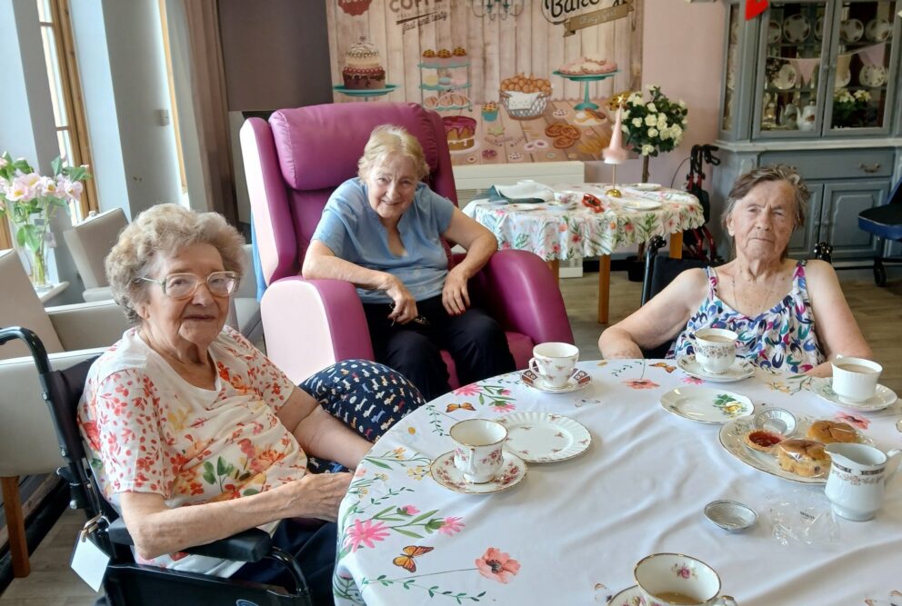 Hafod Housing Asscoaition - Three care home residents sat around a table enjoying a coffee morning