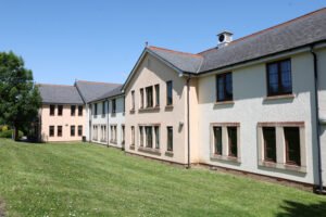 Row of modern residential building with pale rendered walls, dark roofs, and brown window frames.