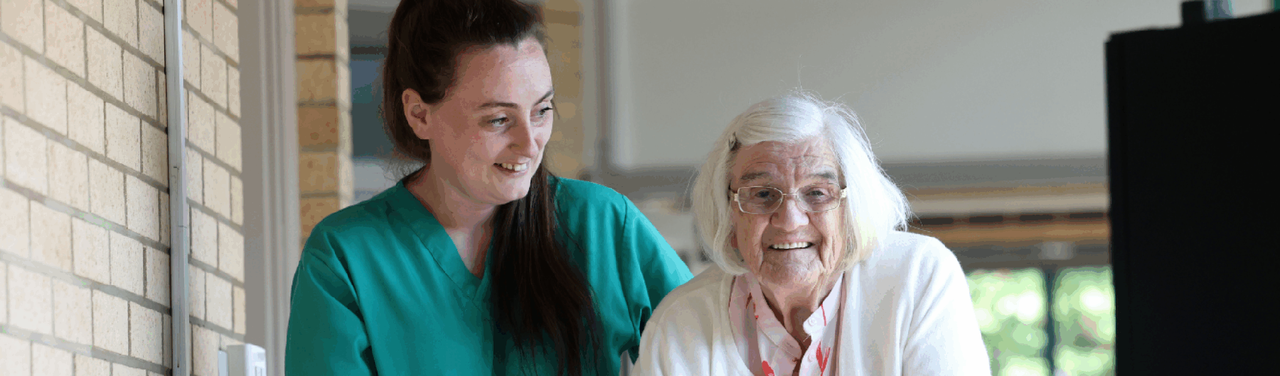 Carer walking with female care home resident happily