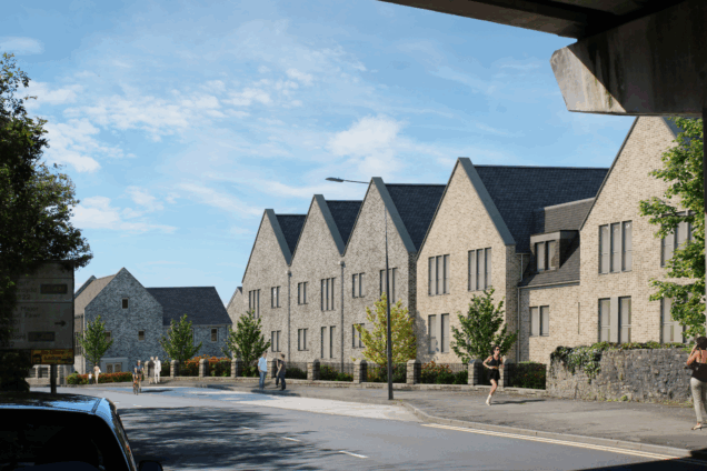 Computer generated image of a row of modern stone buildings with pitched roofs along a street, with trees, a stone wall, and people walking under a clear blue sky