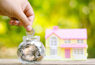 Savings money coins for house with sunlight