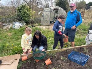 Hafod Housing Association two adults and two children in an allotment planting things