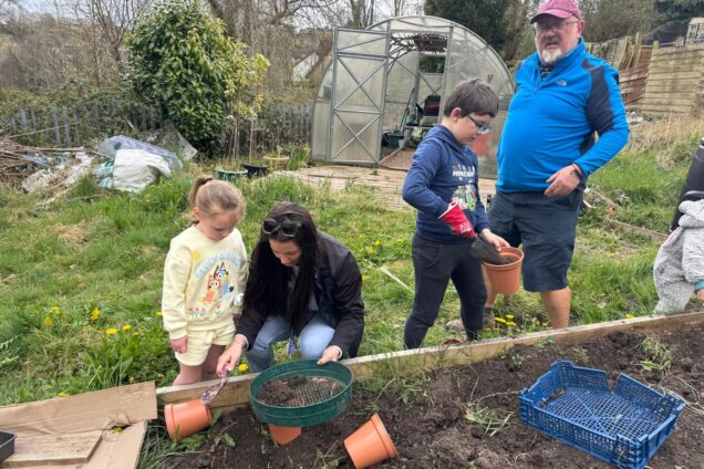 Hafod Housing Association two adults and two children in an allotment planting things