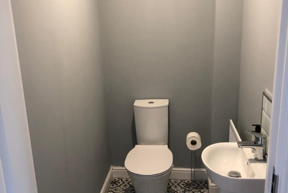 Downstairs toilet with hand basin. Grey-painted walls and patterned flooring.