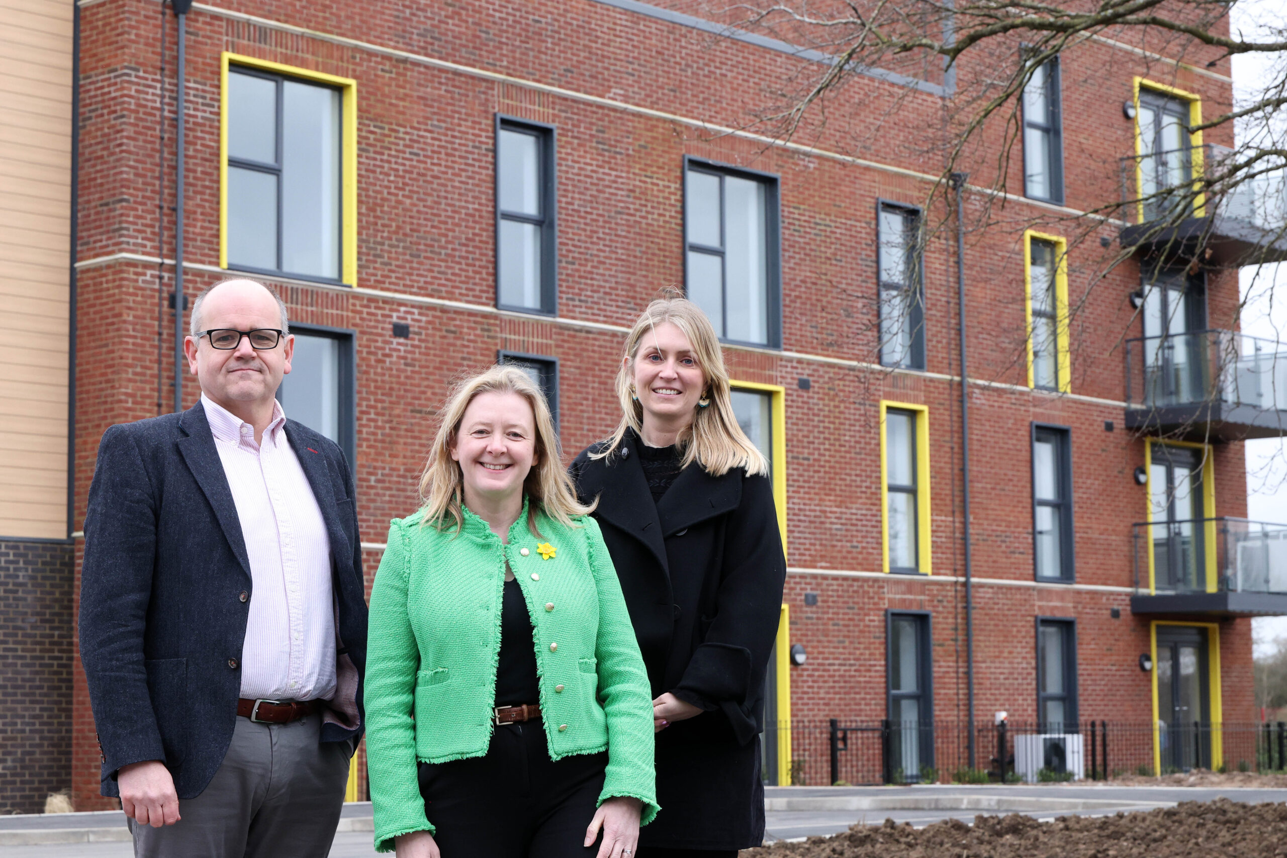Three people stood in front of a new blaock of apartments