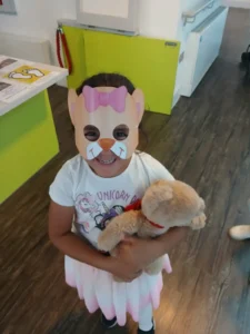 Girl holding a teddy bear wearing a mask
