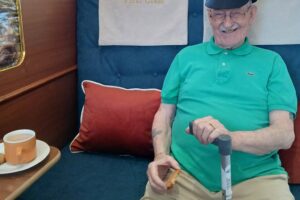 Bernard wearing a train divers hat, smiling aboard the Jolly Journey train carriage