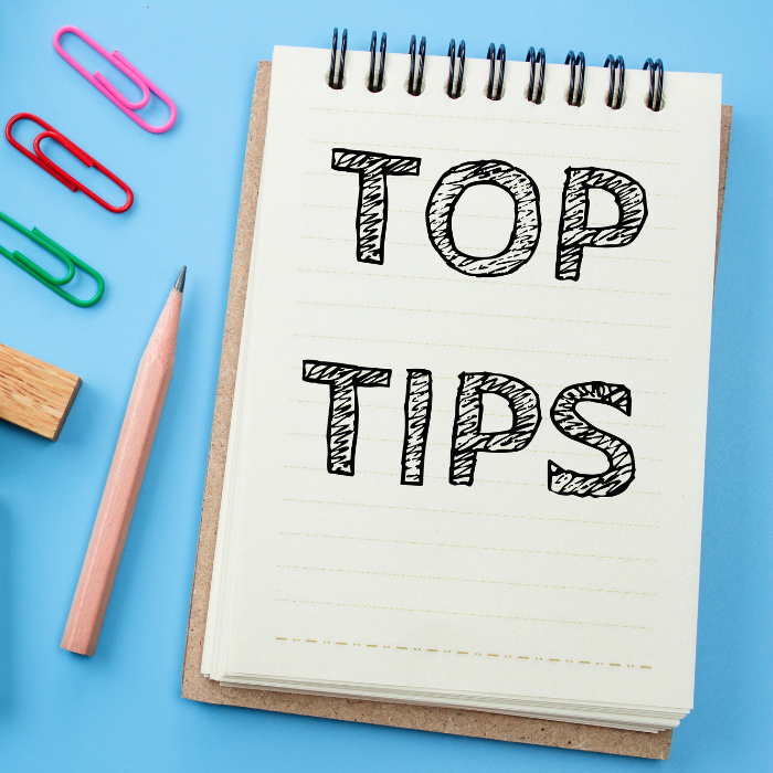 Notepad with the wording top tips written on it with a pencil and paperclips lying to the left hand side of it.